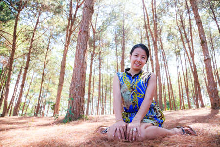 Thai woman sit and smile in pine forestの写真素材