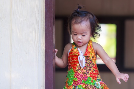 Asian baby girl standing behind the doorの写真素材