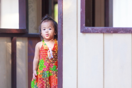 Asian baby girl standing behind the doorの写真素材