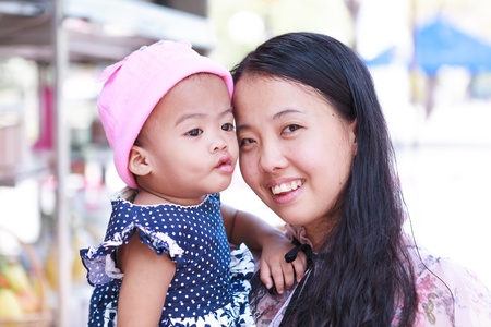 Mother holding daughter in arms and smilingの写真素材