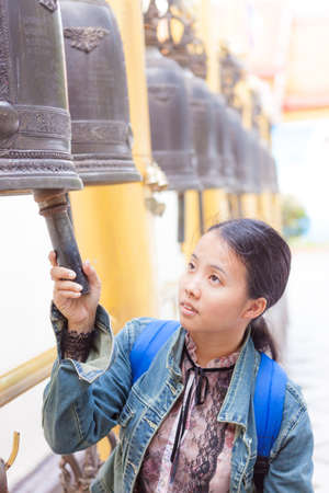 Thai woman hit the bell in templeの写真素材