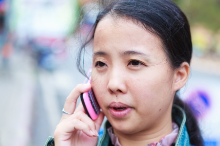 Asian woman in jeans jacket talking to phoneの写真素材