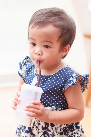 Thai baby girl drinking water by sucking from strawの写真素材