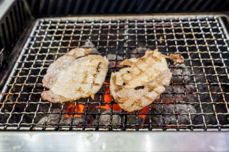 Grilling pork on fire with charcoalの写真素材