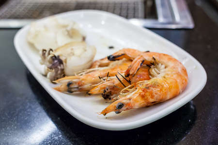 Grilled shrimps on white dish on the tableの写真素材