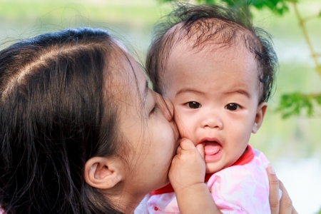 Asian woman holding and kissing her daughterの写真素材