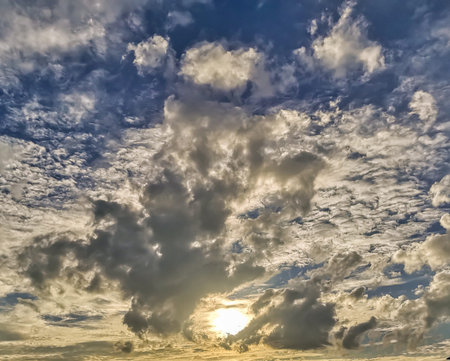 Sun behind clouds with blue sky background