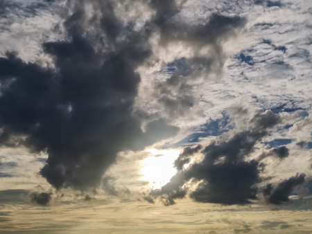 Sun behind clouds with blue sky backgroundの写真素材