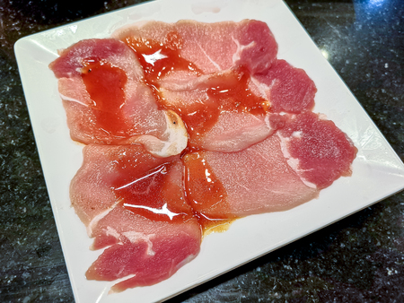 Sliced uncooked raw pork on white dishの写真素材