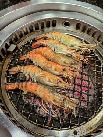 Cooking by grilling prawn on charcoal barbecue stoveの写真素材