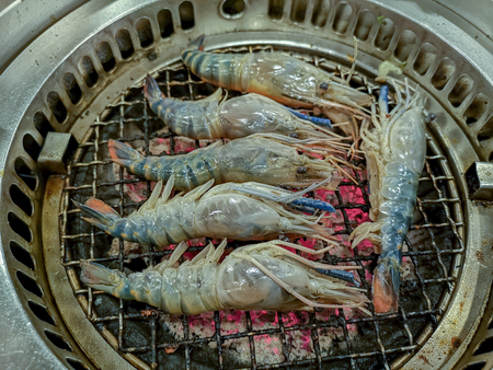 Cooking by grilling prawn on charcoal barbecue stoveの写真素材