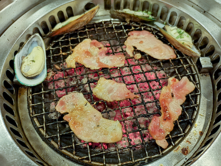 Cooking by grilling sliced pork on charcoal barbecue stoveの写真素材