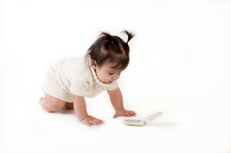 adorable baby girl crawling to phoneの写真素材