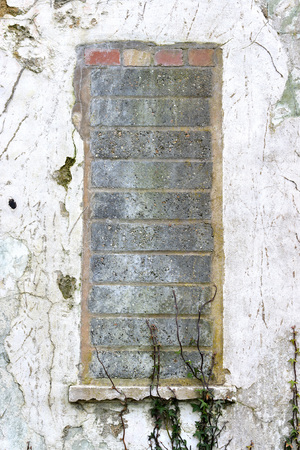 Bricked up window and white wall on derelict buildingの写真素材