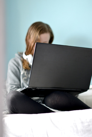 Teen girl on a laptop in her bedroomの写真素材
