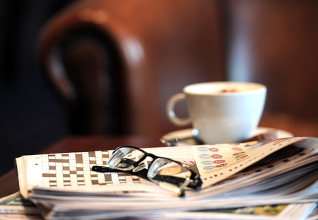 Cup of coffee with newspaper crossword and glasses, ear leather club chair.の写真素材