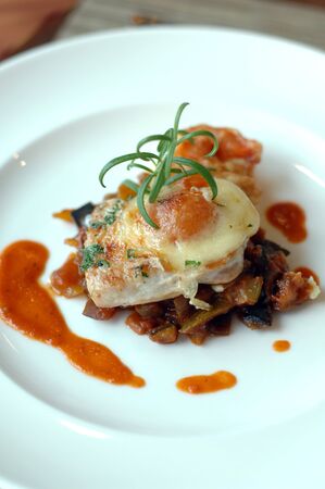 Vegetable lasagne on plain white plateの写真素材