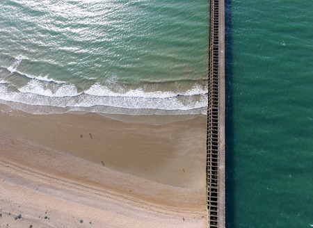 Aerial shot of breakwater and beach with a green seaの写真素材