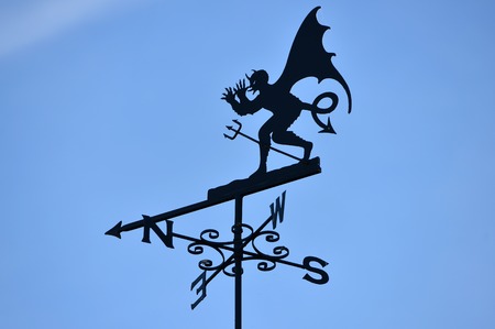 winged Devil or demon weather vane with blue skyの写真素材