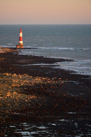 Red and white lighthouse at low tideの写真素材