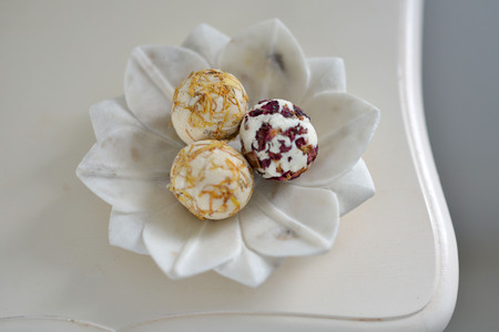 Round colourful bath bombs with flower petals in a bathroomの写真素材