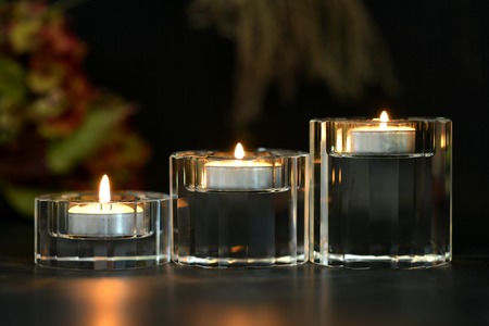 Glass candle holders with green foliage and dark backgroundの写真素材