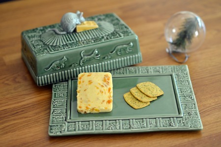 Cheese on a green embossed plate with ceramic mouseの写真素材
