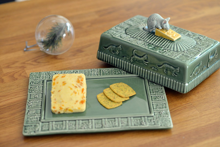 Cheese on a green embossed plate with ceramic mouseの写真素材