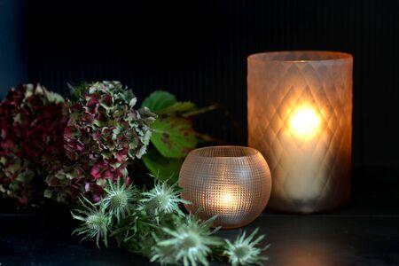 Glass candle holders with green foliage and dark backgroundの写真素材