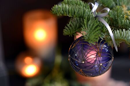Christmas glass baubles with green foliage and candlesの写真素材