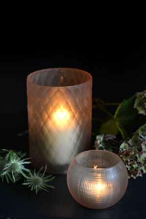 Glass candle holders with green foliage and dark backgroundの写真素材