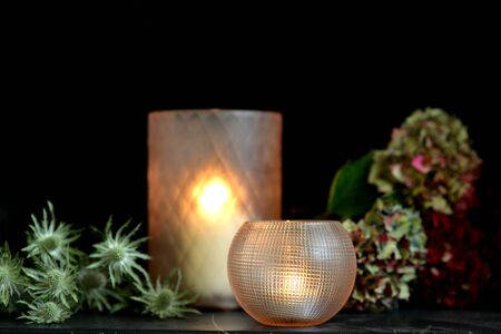 Glass candle holders with green foliage and dark backgroundの写真素材