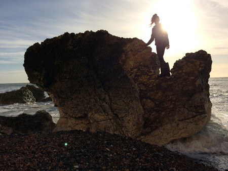 Teen standing in a rock by the seaの写真素材