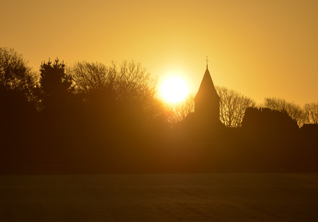 Sun rising behind a small country churchの写真素材