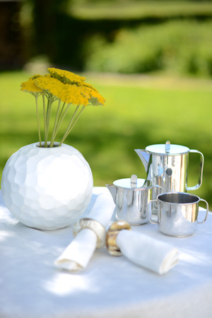 Luxury silver coffee pot on a linen covered table outside in summer.の写真素材