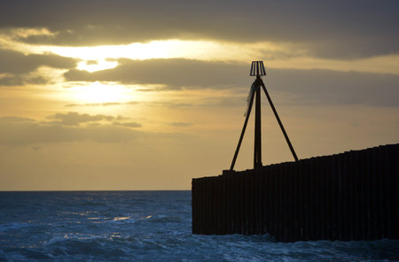 Marker on a jetty in the sea at sunsetの写真素材