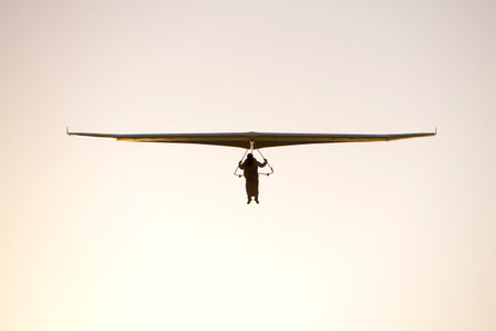Hang glider flying towards the camera at sunset