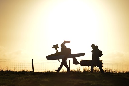 Two people walking with model aircraft at sunsetの写真素材