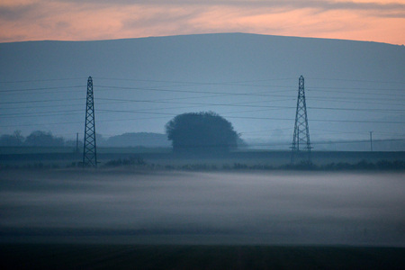 Electricity pylons at dusk with low lying mistの写真素材