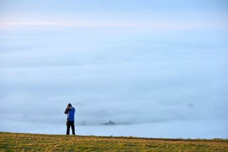 person taking a photograph of low lying mist from the South Downsの写真素材