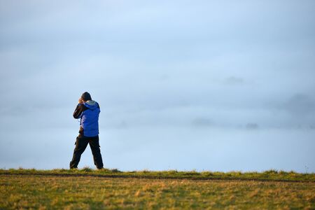 person taking a photograph of low lying mist from the South Downsの写真素材