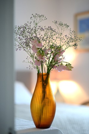 Amber glass fluted vase with flowers in a roomの写真素材