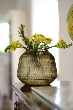 Short brown decorative glass vase with flowersの写真素材