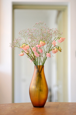 Amber glass fluted vase with flowers in a roomの写真素材