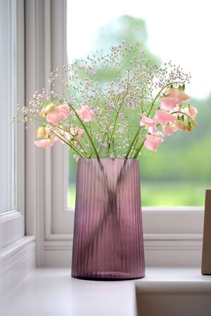 Pink cut glass vase with flowers in a room settingの写真素材