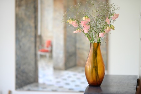 Amber glass fluted vase with flowers in a roomの写真素材