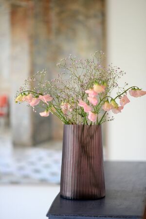 Pink cut glass vase with flowers in a room settingの写真素材