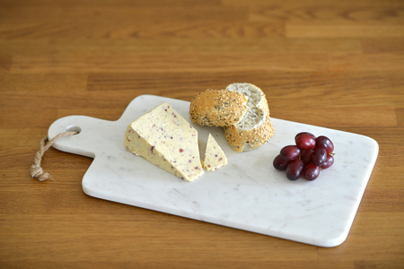 White marble cheese board in a kitchen with cheese and grapesの写真素材