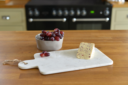 White marble cheese board in a kitchen with cheese and grapesの写真素材