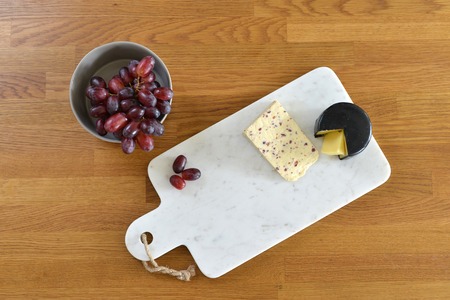 White marble cheese board in a kitchen with cheese and grapesの写真素材